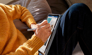 Person i gul sweater tegner på Microsoft Surface tablet