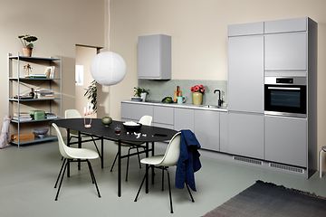 Light grey EPOQ Integra kitchen in an open kitchen solution, with dinner table, chairs and a bookshelf