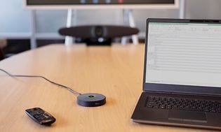 IRIS video konferencesystem på et mødebord ved siden af en laptop