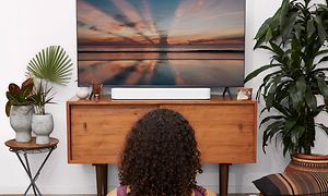 Kvinde laver yoga foran tv med Beam soundbar