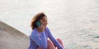 Fairphone 4 i hånden på en kvinde, der sidder ved havet