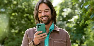 Fairphone 4 i hånden på en mand, der kigger på sin telefon