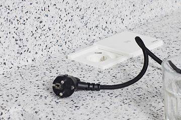 Sort ledning ved siden af en stikkontakt integreret i en køkkenbordplade