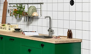 Et grønt køkken med træbordplade og forskelligt udstyr