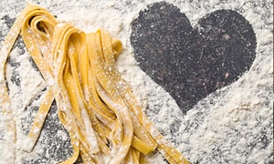 hjemmelavet pasta og et hjerte formet i mel på bordet ved siden af