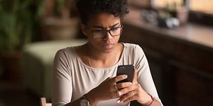 Kvinde holder en smartphone, som hun kigger på