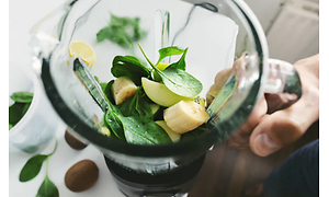 Blender fyldt med skåret frugt og blade