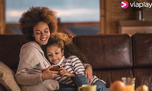 Mor og datter i en sofa ser på smartphone