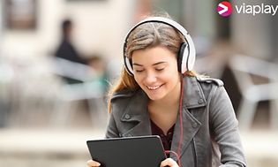 Ung pige med hovedtelefoner ser på tablet