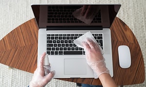 Person gør en bærbar computer rent med papir