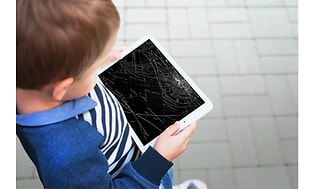 Et barn, der holder en tablet med en ødelagt skærm