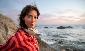 Bose headphones-woman by the sea with Bose QC45 headphones around the neck