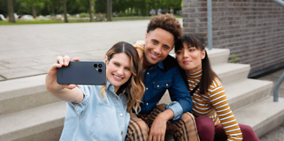 Fairphone 4 i hånden på en kvinde, der tager en selfie med to andre