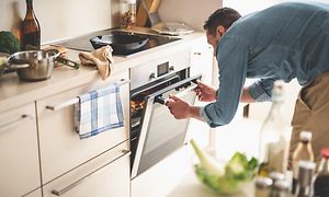 Mand i et køkken åbner ovn for at se ind til en madret