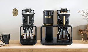 To sorte kaffemaskiner på et bord