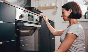 Kvinder sidder på hug og kigger ind i en ovn