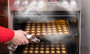 To varme bradepander med småkager på vej ud af en ovn