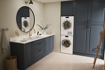 Moderne badeværelse i blå farve og rundt spejl, vaskemaskine og tørretumbler