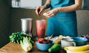 Kvinde laver en smoothie med jordbær og banan