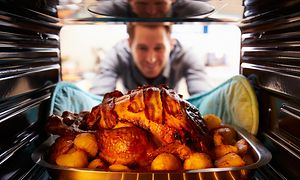 Mand tager grillet kylling ud af ovnen