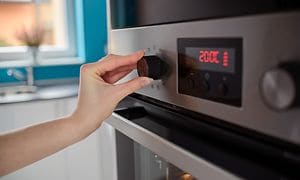 Hånd justerer temperaturen på en indbygget ovn