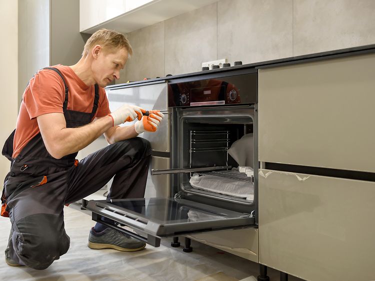 Mand installerer en ovn i et grønt køkken