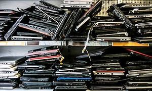 En stak gamle bærbare computere på en hylde