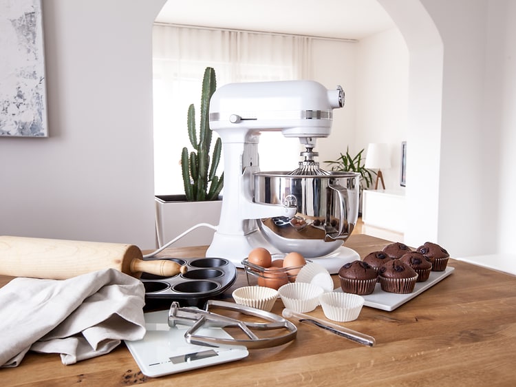 Køkkenmaskine på et køkkenbord sammen med æg og muffins