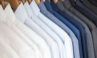 Skjorter i forskellige farver hænger på bøjler i en række