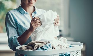 Kvinde folder vasketøj fra en vasketøjskurv