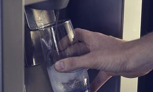 Person fylder et glas vand via en vanddispenser