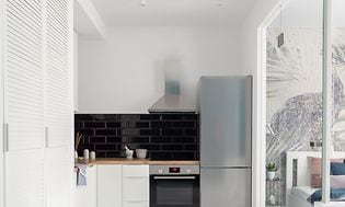 Et lille hvidt køkken med stål køleskab