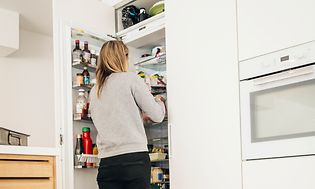 Kvinde og baby kigger ind i køleskab for at finde mad