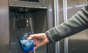 Mand fylder vand i et glas ved en vandautomat