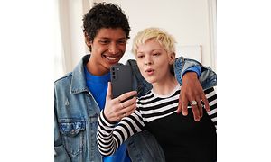 Samsung Galaxy S21 FE i hånde på kvinde, som tager en selfie sammen med en mand, der har lagt armen om hende