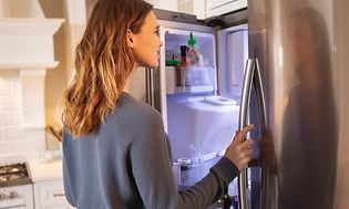 Kvinde åbner og kigger ind i et køleskab