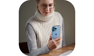 En ung kvinde, der holder en iPhone 13 i hånden