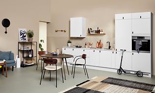 Hvidt EPOQ Core køkken i en åben køkkenløsning med sofa og spisebord