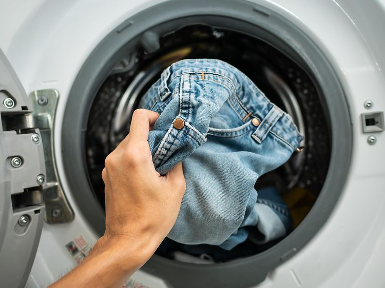 MDA-vaskemaskine-et par jeans lægges i vaskemaskinen
