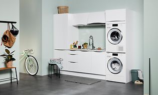 Hvid EPOQ Gloss White vaskerum i en åben bryggersløsning med en vaskemaskine og en tørretumbler