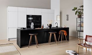 Hvidt EPOQ Integra køkken i en åben køkkenløsning med barstole og en sort køkkenø