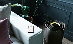 En sort Pure A9 stående ved siden af en sofa med en telefon ovenpå