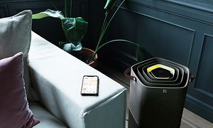 Luftrenser - En sort Pure A9 stående ved siden af ​​en sofa med en telefon liggende ved armlænet