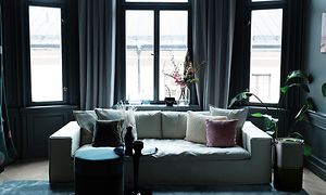 en sort Pure A9 stående ved siden af en lys sofa i en mørk stue