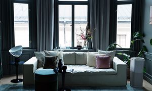 En høj grå Pure A9 stående i et mørkt rum ved siden af en lys sofa