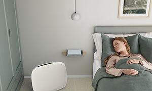 En dame, der sover i sin seng med en hvid Well A5 på gulvet ved siden af sig