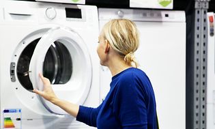 En kvinde, der ser på ny vaskemaskine hos Elgiganten