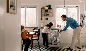 En mand og børn tager opvasken ud af en integreret opvaskemaskine