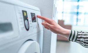 Kvinde bruger display og knap til at tænde og vælge cyklusprogram på vaskemaskinen
