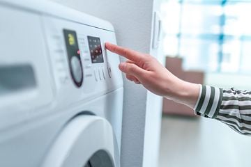 Kvinde bruger display og knap til at tænde og vælge cyklusprogram på vaskemaskinen
